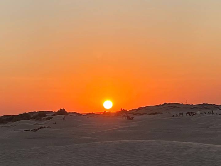 Coucher de soleil sur les dunes de sable, avec le soleil près de l'horizon.