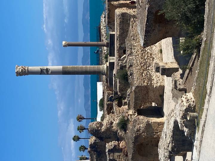 Ruines romaines avec des colonnes et la mer en arrière-plan.