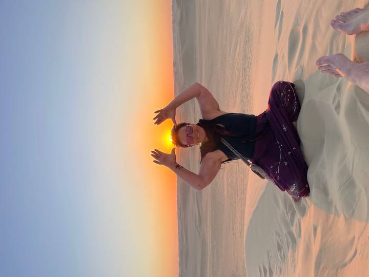 Personne qui pose dans un décor désertique au coucher du soleil.