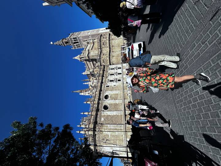 Des personnes posant devant un complexe de bâtiments historiques avec une haute tour.