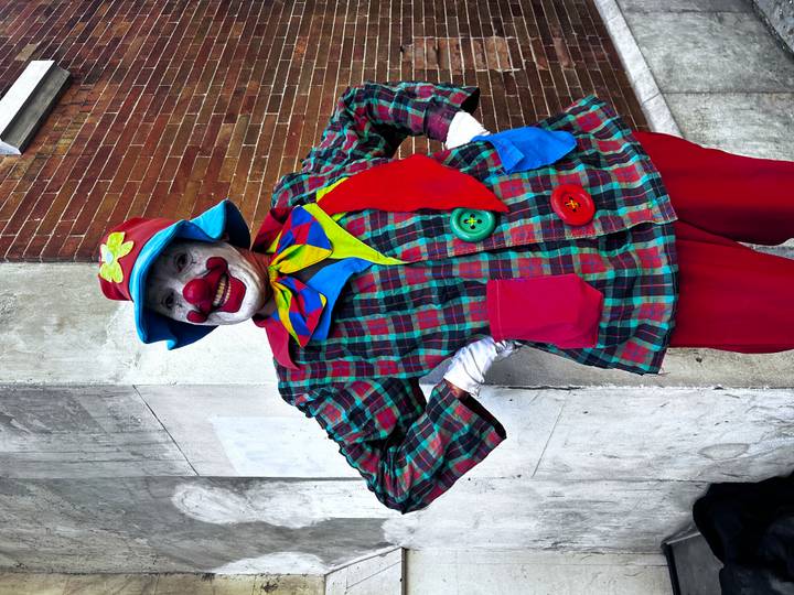 Personne déguisée en clown avec des vêtements colorés qui pose.
