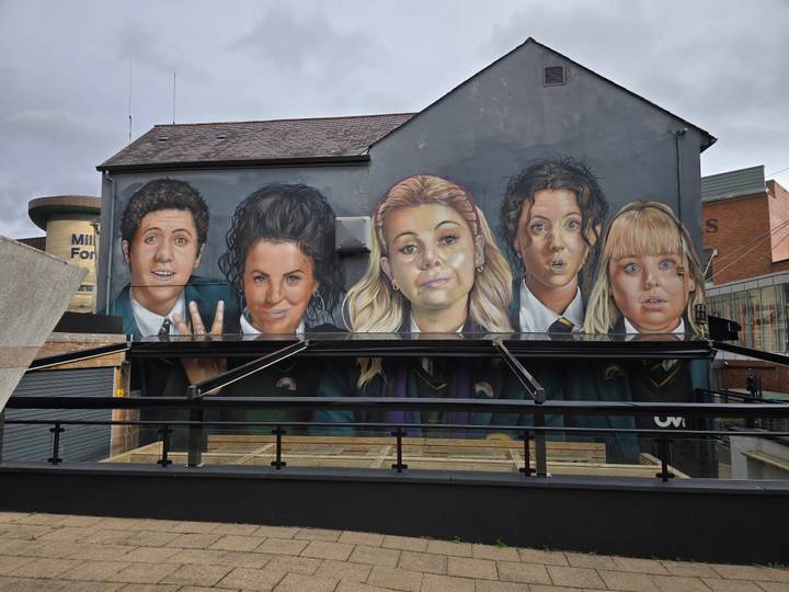 Une fresque avec cinq personnages peints sur le mur d'un bâtiment.