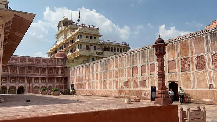 Innenhof eines historischen rosa und gelben Palastes mit kunstvoller Architektur in Jaipur, bekannt für seine Paläste und Festungen.