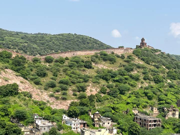 Bewaldete Hügel mit einer ausgedehnten Mauer und einem kleinen Turm auf dem Gipfel.