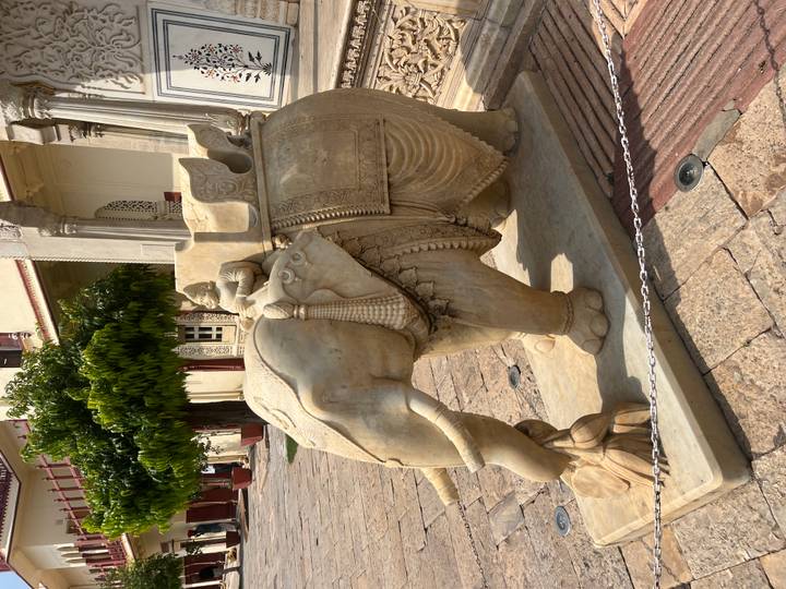 Steinstatue eines Elefanten mit kunstvollen Schnitzereien in einem Innenhof.