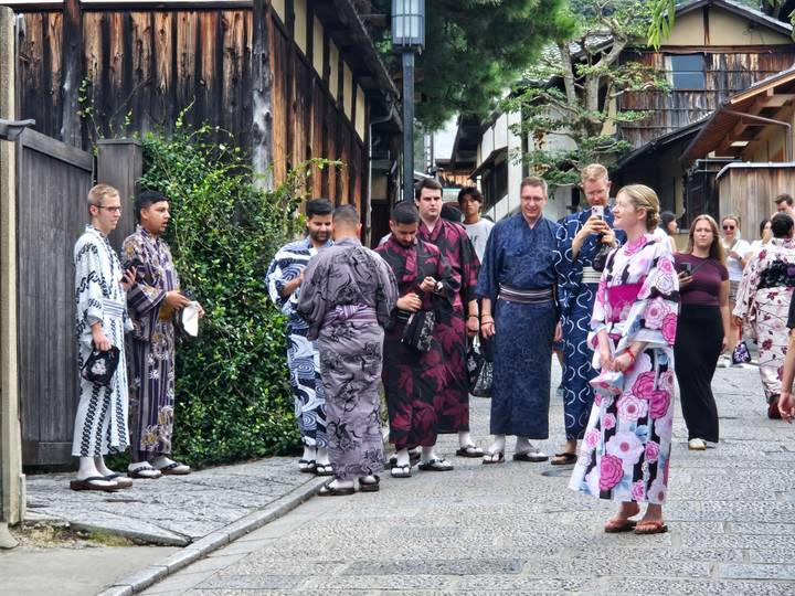 Groupe de touristes en tenue japonaise traditionnelle dans une rue.