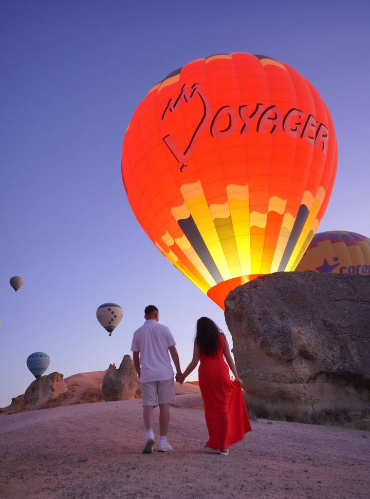 Couple regardant des montgolfières dans un ciel crépusculaire.
