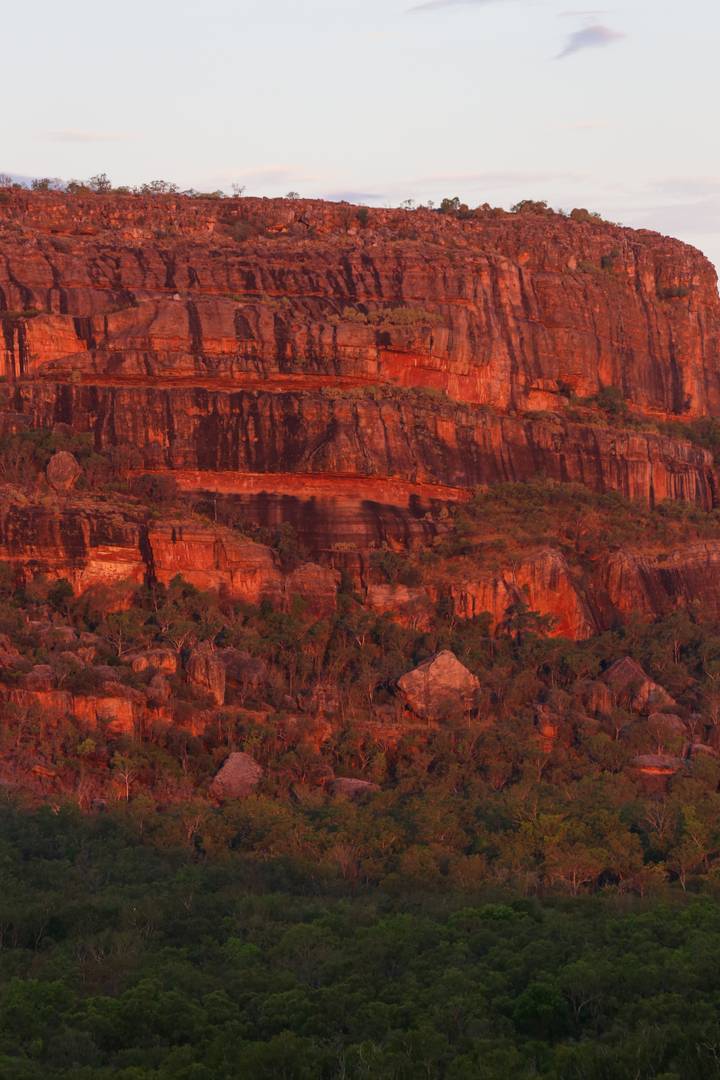 Zerklüftete rote Felsklippen, die von Sonnenlicht beleuchtet werden.