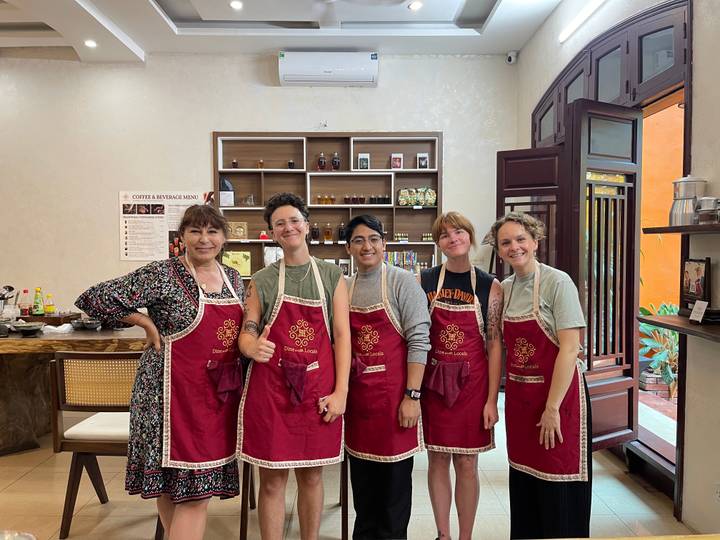 Groupe de personnes posant dans un cadre de cours de cuisine portant des tabliers.