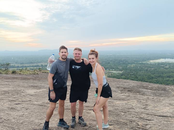 Trois personnes posant sur un affleurement rocheux avec vue.