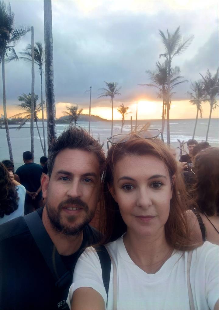 Gros plan de deux personnes avec un coucher de soleil sur la plage en arrière-plan.