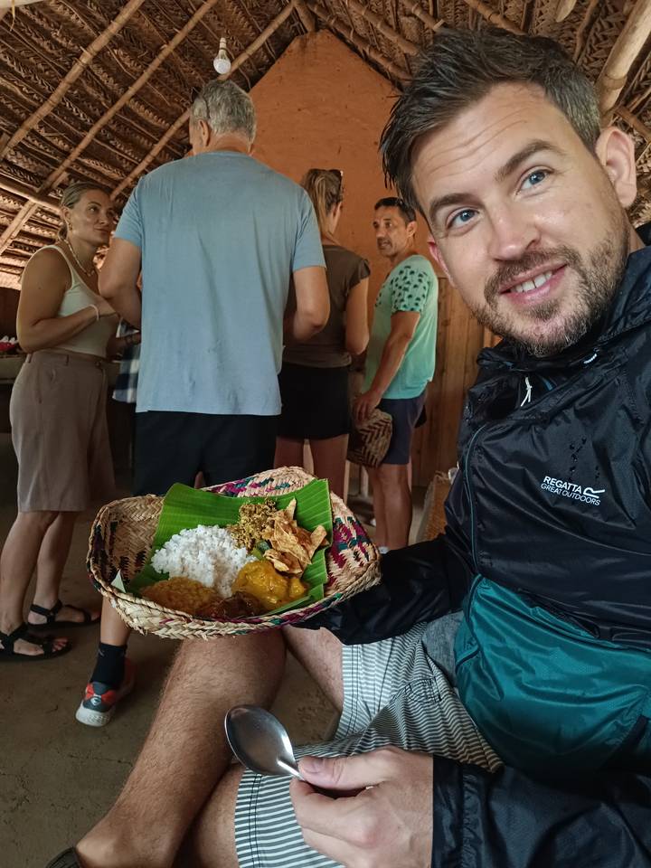 Personne avec une assiette de nourriture présentée sur des feuilles de bananier.