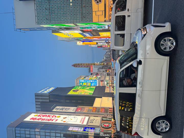 Rue animée de la ville au crépuscule avec des enseignes éclairées.