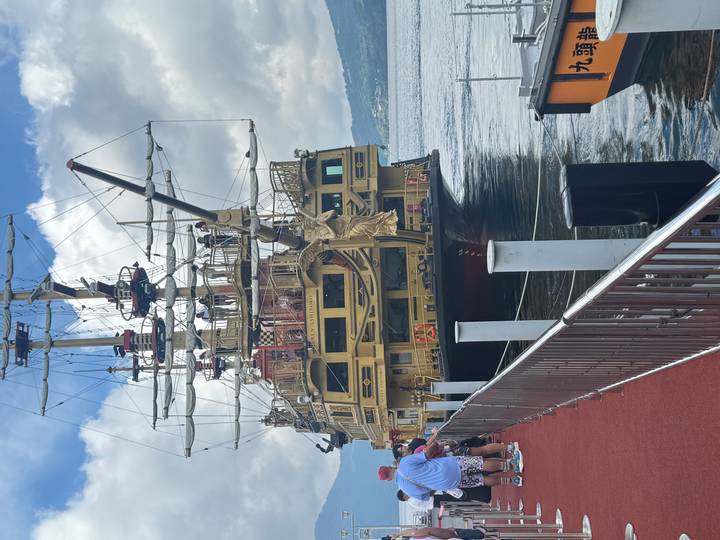 Des touristes embarquant sur un grand navire de croisière de style pirate.