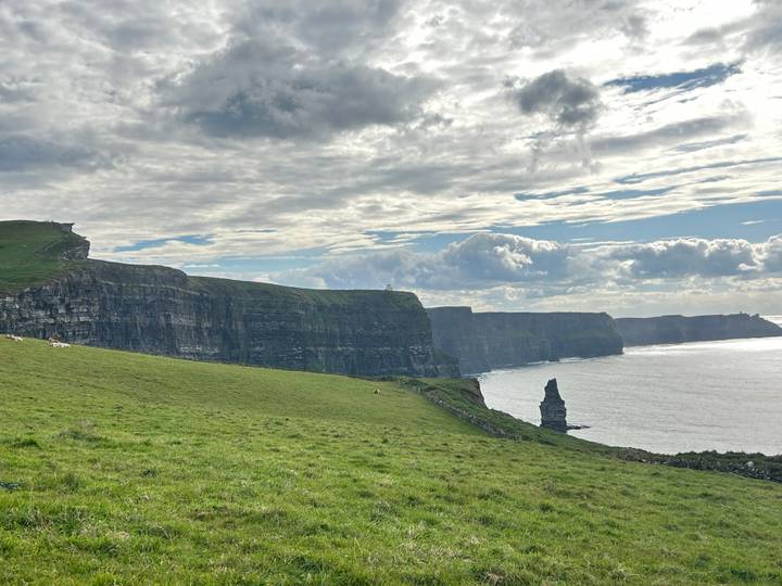 Vue panoramique des falaises de Moher avec de l'herbe verte and l'océan.