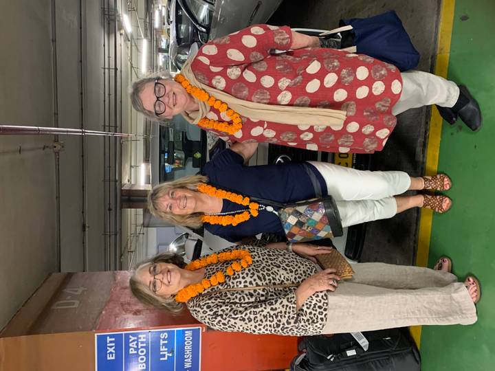 Trois femmes portant des guirlandes de fleurs dans un garage de stationnement.