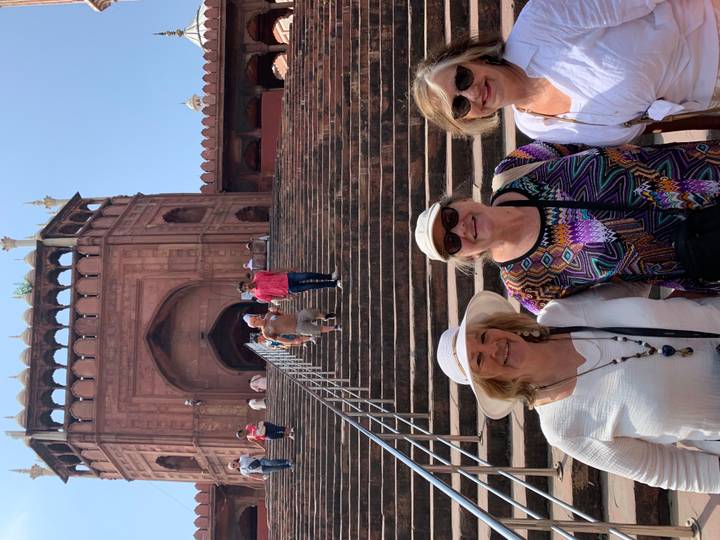 Trois femmes devant un bâtiment historique avec des escaliers.