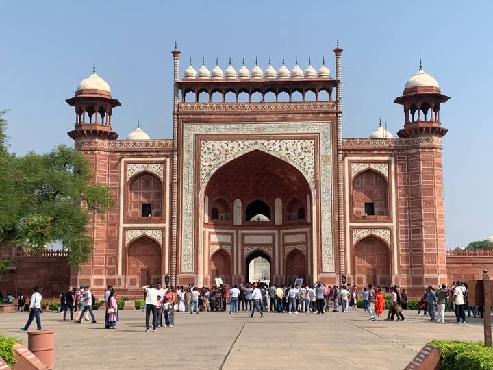 Une grande foule de personnes devant un grand portail rouge et blanc.