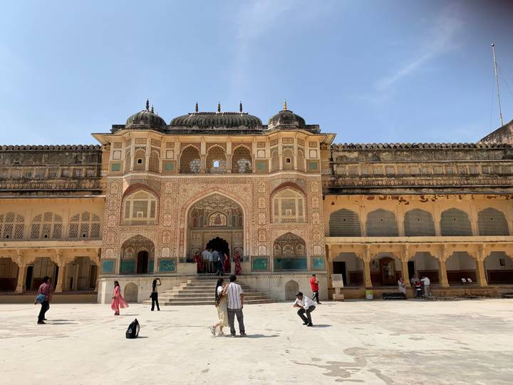 Des personnes explorant une cour avec une entrée magnifiquement décorée.