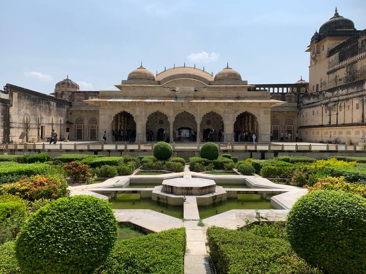 Un jardin avec des haies taillées devant un bâtiment historique.