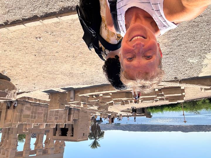 Une personne devant des ruines au bord de l'eau.