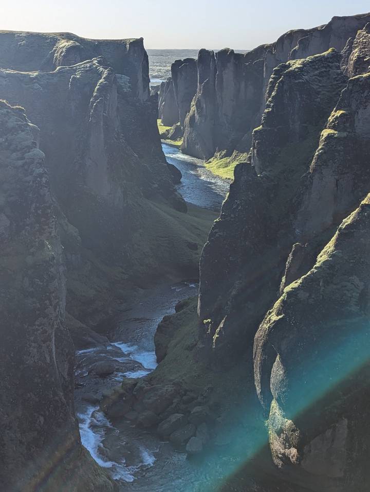 Gorge de rivière avec des parois rocheuses escarpées et la lumière du soleil qui filtre à travers.