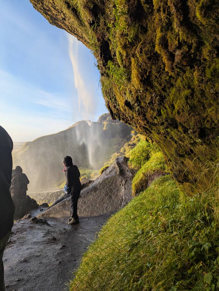 Des gens assis sur des rochers près d'une grande cascade.