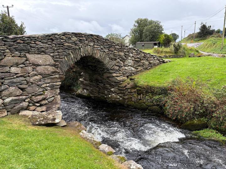 Pont de pierre au-dessus d'une rivière qui coule, verdure luxuriante alentour, Irlande.