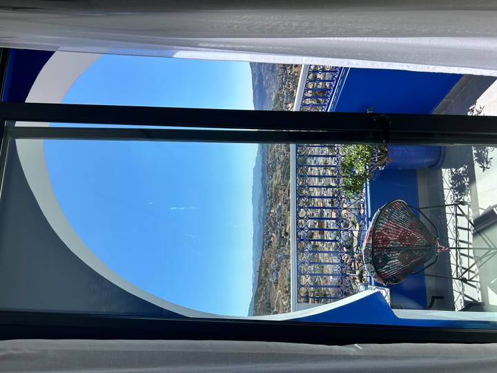 Vue depuis un balcon surplombant des collines et une ville, probablement Chefchaouen.