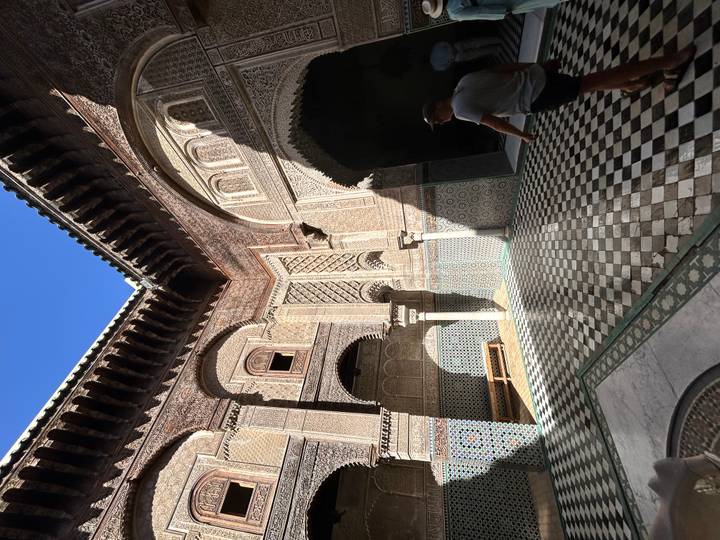 Cour avec des détails architecturaux complexes et une personne qui marche.