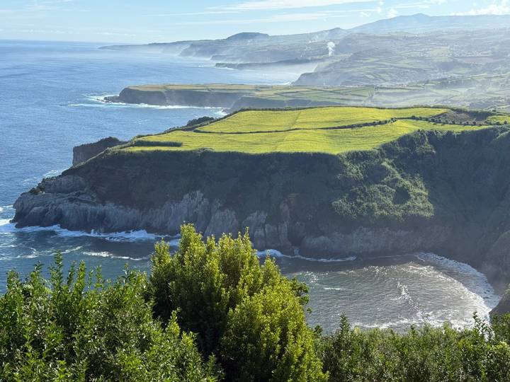 Falaise avec des pâturages verts au-dessus d'un océan.