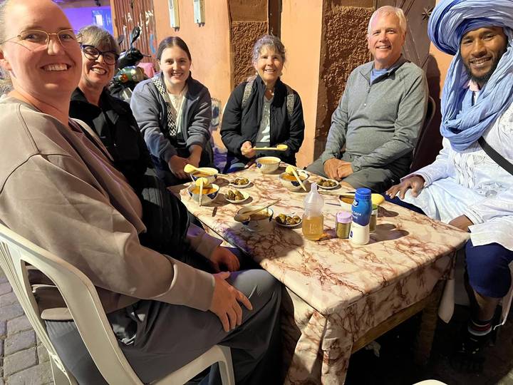 Un groupe de personnes assises à une table avec des assiettes de nourriture et des boissons.