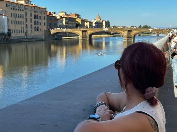 Une personne qui se détend près d'une rivière avec un pont en arrière-plan.