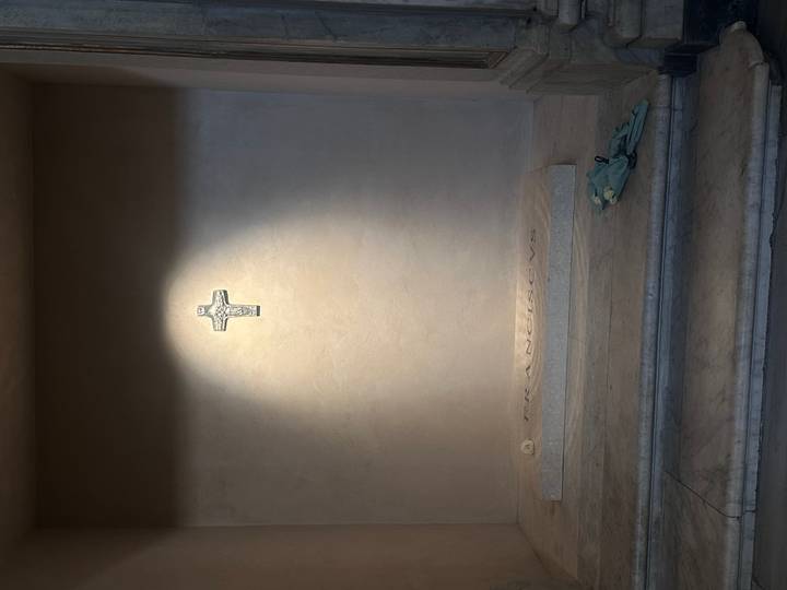 Une simple tombe de pierre avec une croix et des inscriptions.