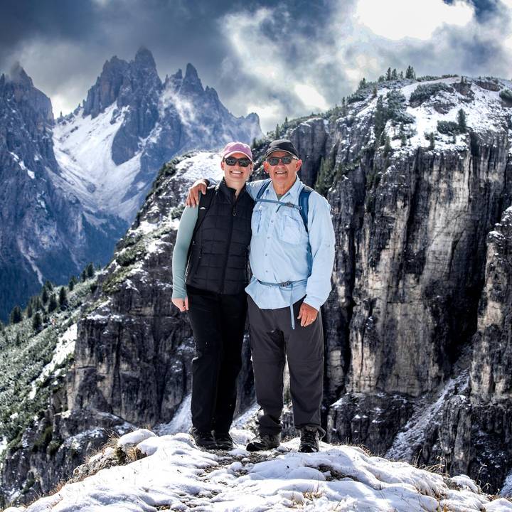 Couple posant avec un paysage de montagne enneigée en arrière-plan.