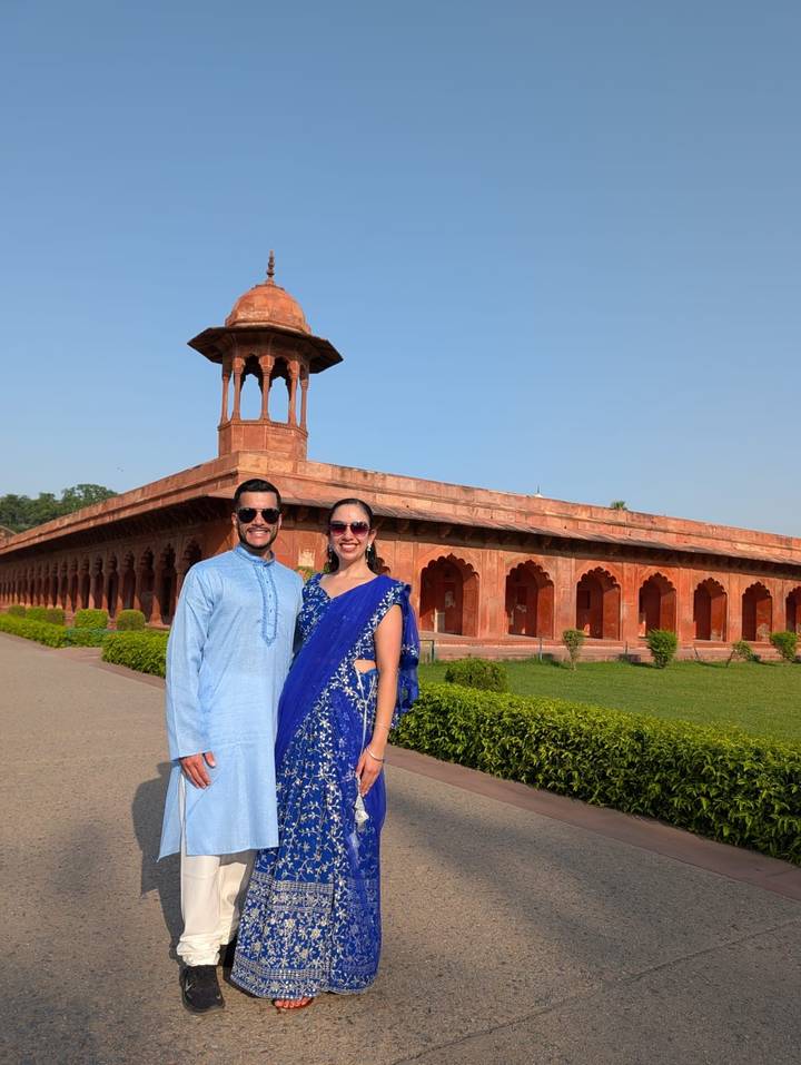 Couple posant en tenue traditionnelle devant un bâtiment historique.