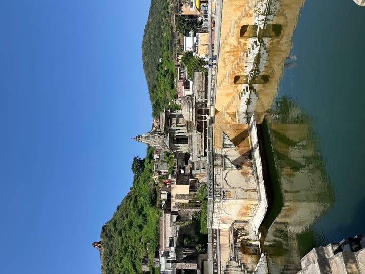 Bâtiment historique avec un point d'eau et paysage environnant.