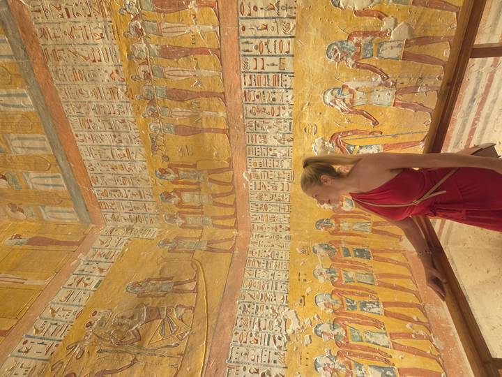 Touriste admirant l'art mural de l'Égypte ancienne.