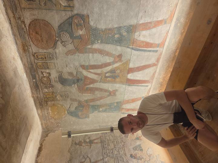 Touriste assis devant des peintures égyptiennes anciennes.