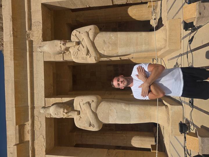 Touriste posant avec des statues dans un temple ancien.