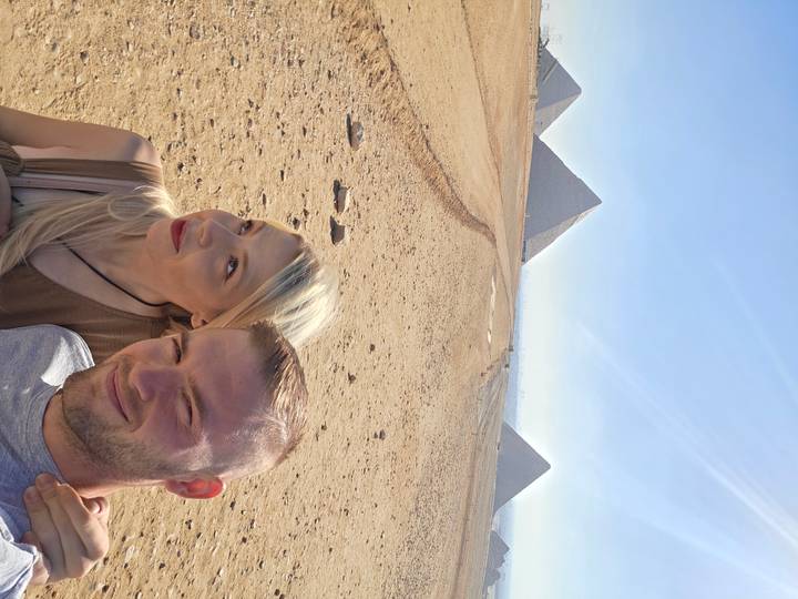 Des touristes avec des pyramides en arrière-plan sous un ciel dégagé.