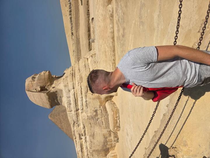 Touriste devant le Grand Sphinx et une pyramide.