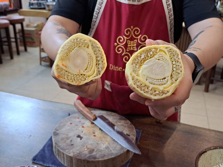 Personne tenant deux moitiés d'un fruit main de Bouddha dans un cadre de cuisine.