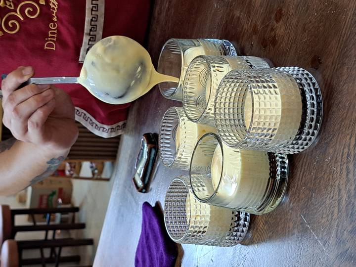 Personne versant un mélange dans des verres sur un comptoir en bois.