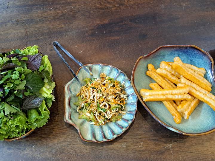 Ingrédients de salade et collations frites sur une table en bois.