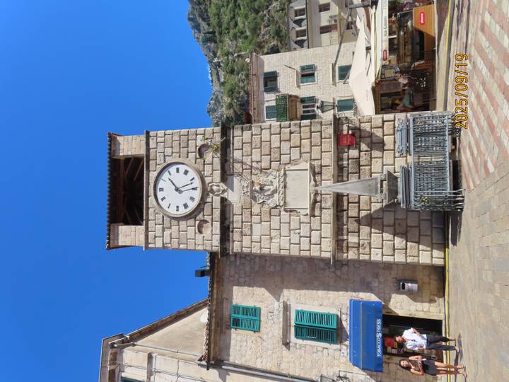 Tour de l'horloge avec des statues sous un ciel bleu dégagé.