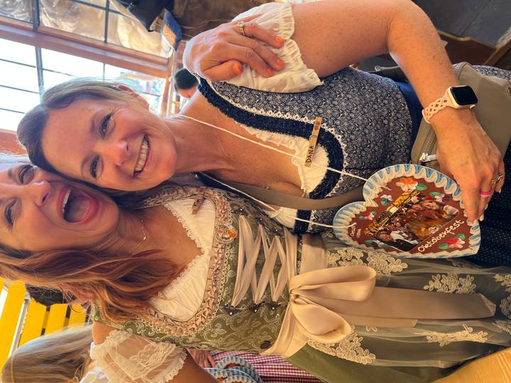 Two women posing with an Oktoberfest heart-shaped cookie.