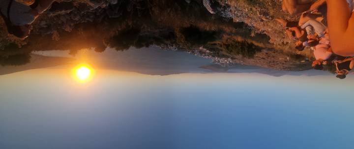 Vue du coucher de soleil d'une ville côtière avec des gens assis