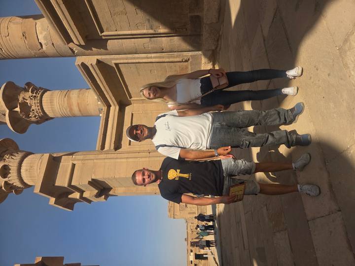 Trois personnes posent devant les colonnes du temple de Philae.