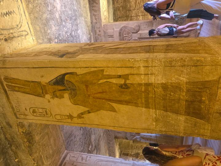 Femme debout à côté d'un pilier antique avec de l'art égyptien.